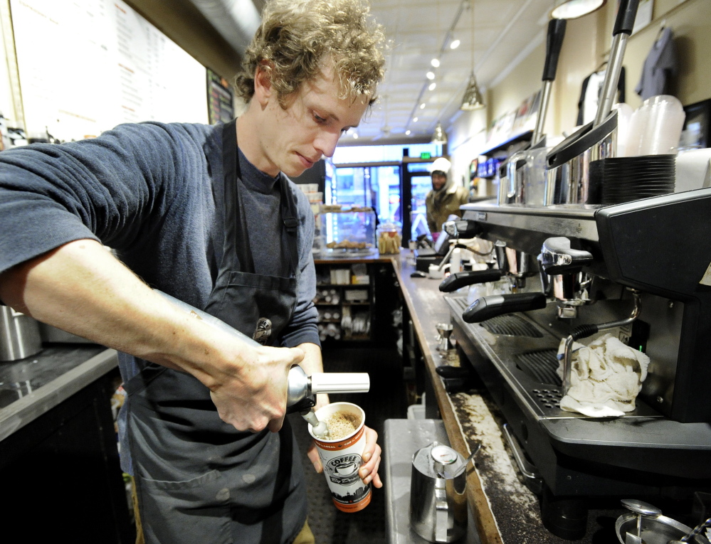 Elliot Conrad makes a hot chocolate drink at Coffee by Design on Congress Street in Portland. He earns $8 an hour, 50 cents more than the state’s minimum wage.