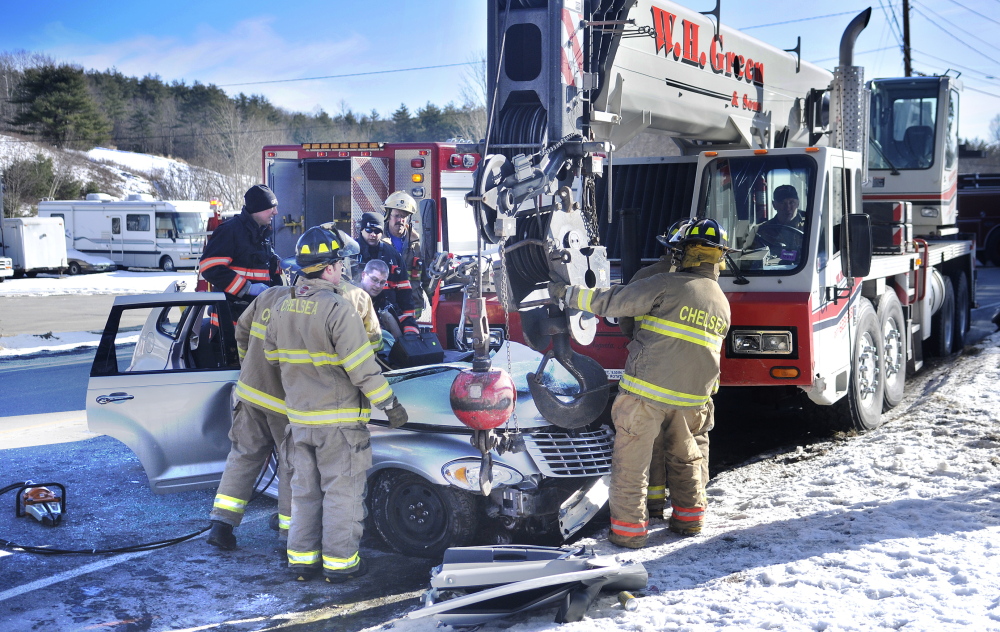 COLLISION: Firefighters and police work at extricating Sally Grouse of Chelsea, who was trapped in her car after pulling out of her driveway into the path of a crane Thursday afternoon on Route 9.
