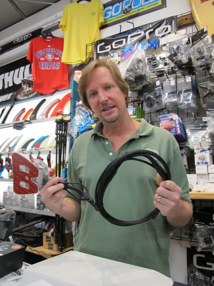 Dennis O’Donnell shows the Shark Shield deterrent device at his Maui store, Hawaiian Island Surf and Sport, in Kahului, Hawaii.