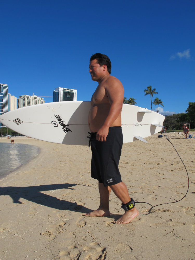 Rudy Aguilar models a shark deterrent device, the Electronic Shark Defense System, attached to his ankle and surfboard in Honolulu recently.
