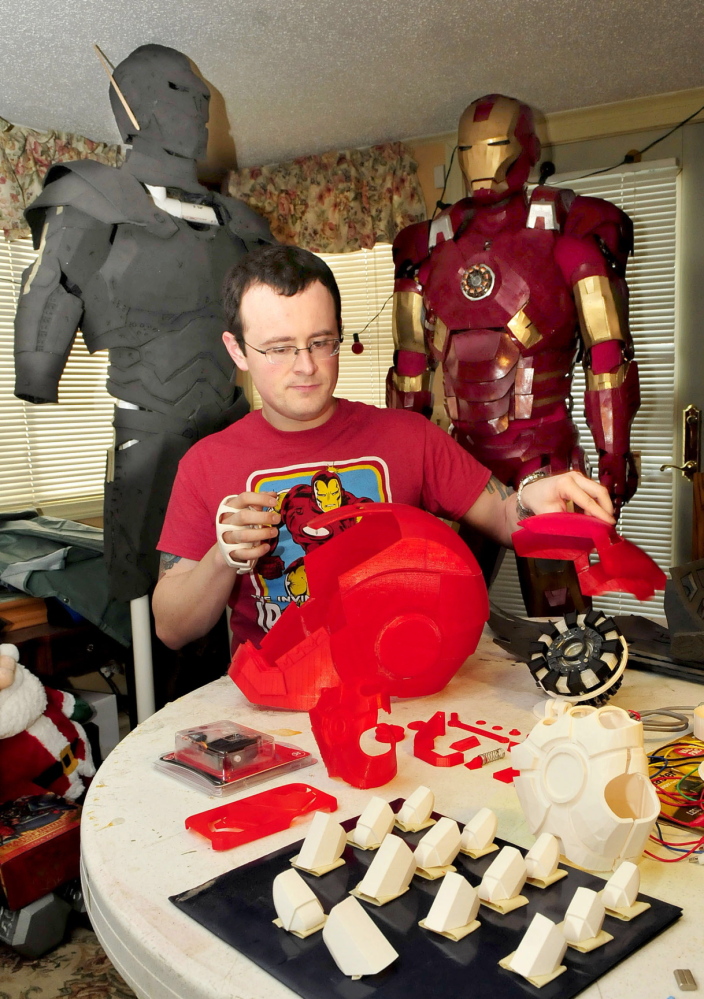 NEW AGE SCIENCE: Tom Lemieux assembles helmet pieces of his new Iron Man character outfit that were made from a 3-D printer and will replace the original outfit, at right.