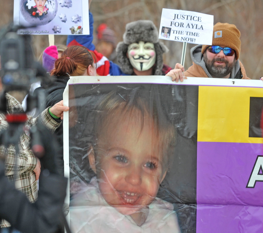 unsolVed: Protesters hold a large sign of missing toddler Ayla Reynolds during a protest about the unsolved case Saturday in Waterville.