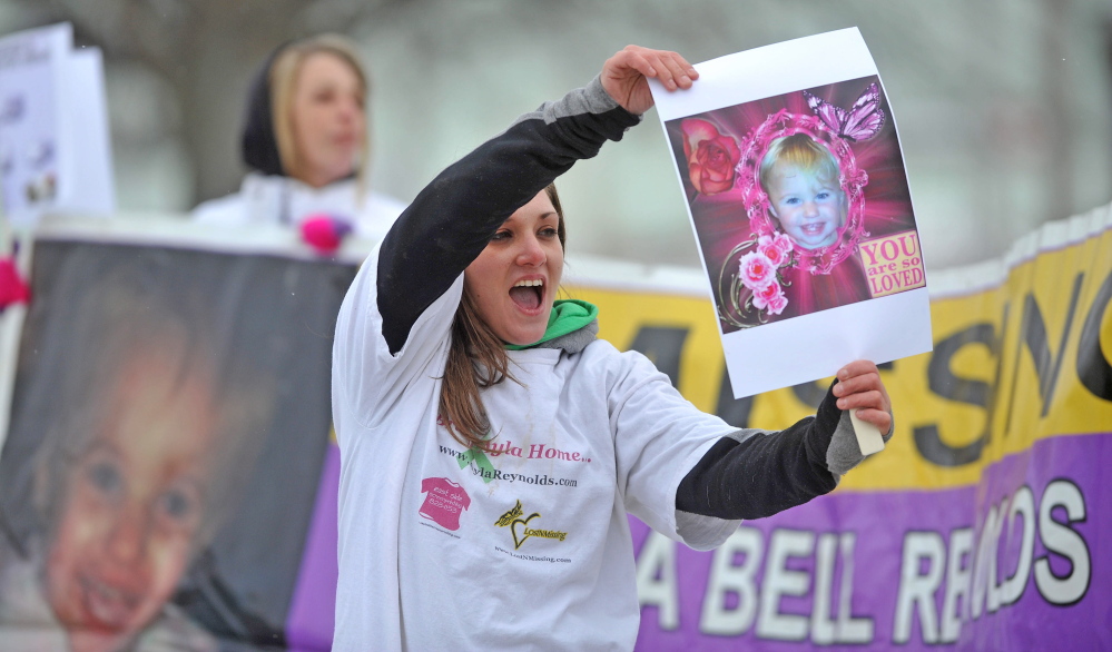remember: Trista Reynolds, mother of missing toddler Ayla Reynolds, holds a picture of her daughter at the Colby Circle and College Avenue intersection in Waterville on Saturday.