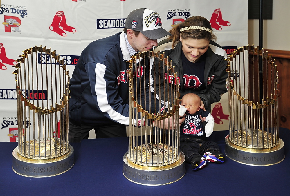 Devan Knight, left, and Ashli Canabush of Lisbon Falls, sit their 2-week-old baby, Brayden, among the three World Series trophies on display at Hadlock Field on Saturday. Devan Knight was a group sales employee for the Sea Dogs in the past.