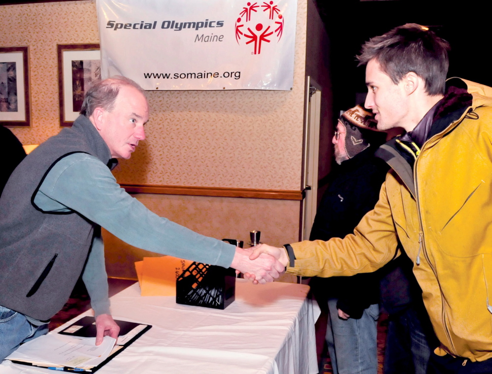 WELCOME: Phil Geelhoed, left, president and CEO of Special Olympics Maine, greets Joshua Nougaret at the volunteer headquarters of the 45th annual Special Olympics Maine Winter Games at Sugarloaf USA on Sunday. Ron Goldstein is in background. Two days of skiing, skating, snowshoe competition and camaraderie begins Monday.