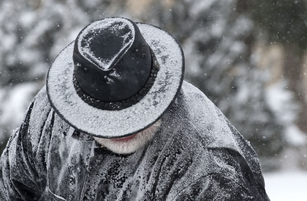 Roger Homrich has snow accumulate on his hat and jacket as he clears snow from a Bridge St. sidewalk in Grand Rapids, Mich., Monday, Jan. 27, 2014. Grand Rapids is experiencing single digit temperatures and sub-zero wind chills.