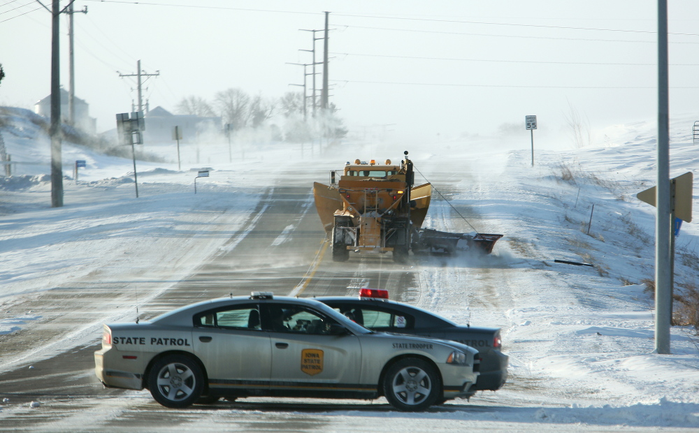 Iowa state patrol officers block Sundown Road going south out of Peosta, Iowa, on Monday due to heavy drifting and blowing snow.