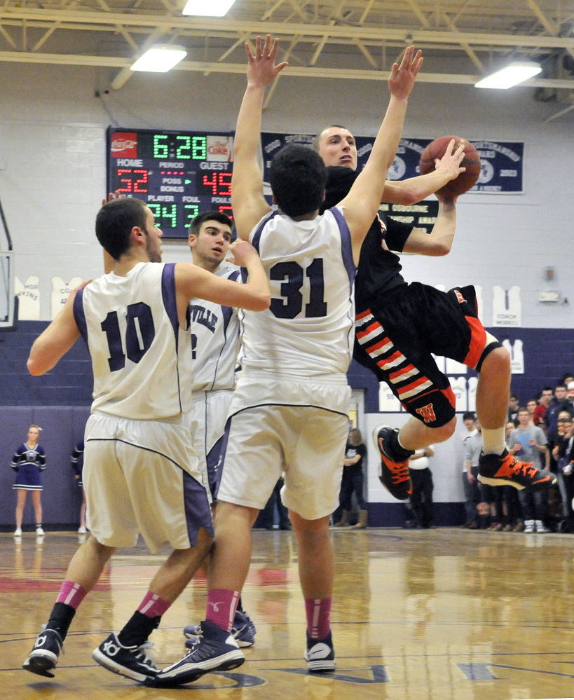 Staff photo by Michael G. Seamans Winslow High School's Trevor Lovely, 3, drives past Waterville Senior High School defenders in the fourth quarter in Waterville on Tuesday. Winslow defeated Waterville 59-54.