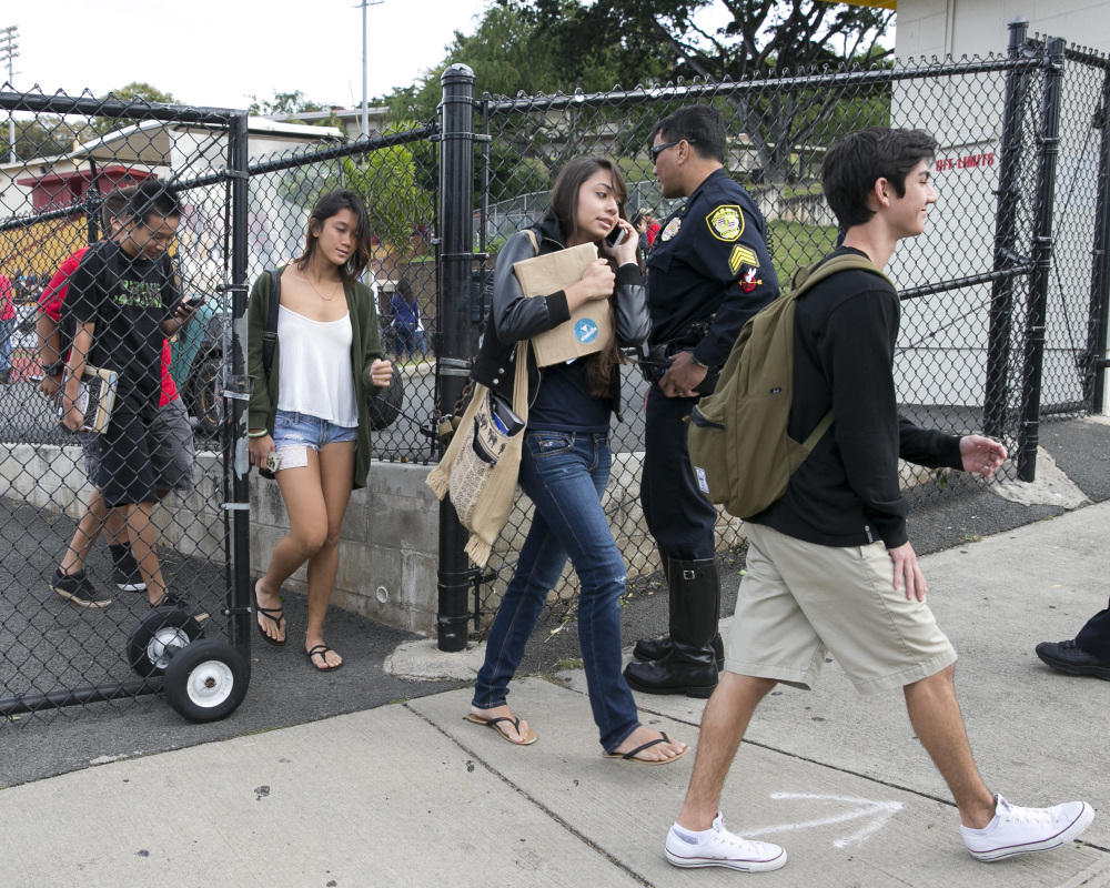 Students leave Roosevelt High School in Honolulu on Tuesday after a police officer shot a 17-year-old runaway in the wrist at the high school after the teen cut one officer with a knife and punched two others, authorities said.