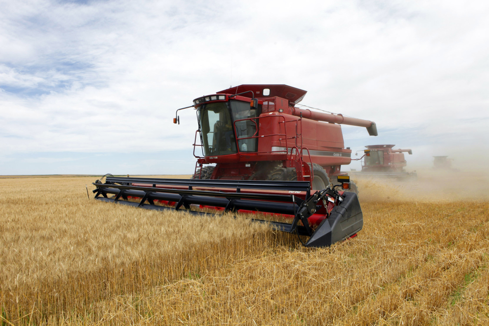 Three combines harvest winter wheat near Roggen, Colo. The House passed a farm bill Wednesday that continues to heavily subsidize major crops.