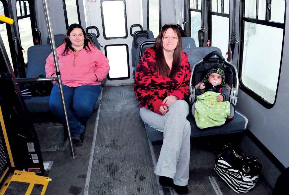 BUS STOPS HERE: Liza Dawes, left, of Madison and Star DeBerry and son Trigger of Skowhegan wait in a Somerset Explorer bus for more passengers Wednesday in the downtown municipal parking lot in Skowhegan. The bus service is getting a new bus shelter as part of the $400,000 revitalization of the parking lot.