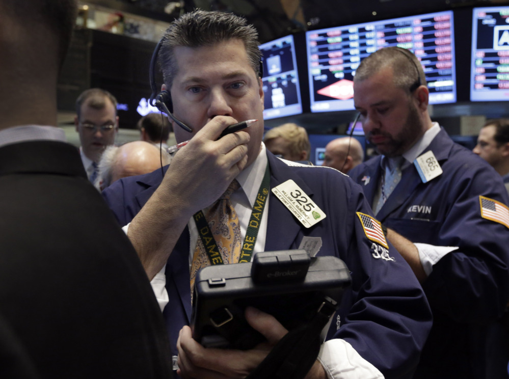 Trader William McInerney, left, works on the floor of the New York Stock Exchange on Wednesday. Weak earnings from several U.S. companies dented investors’ confidence, which then dipped even lower after the Fed announced it was scaling back stimulus bond buying.