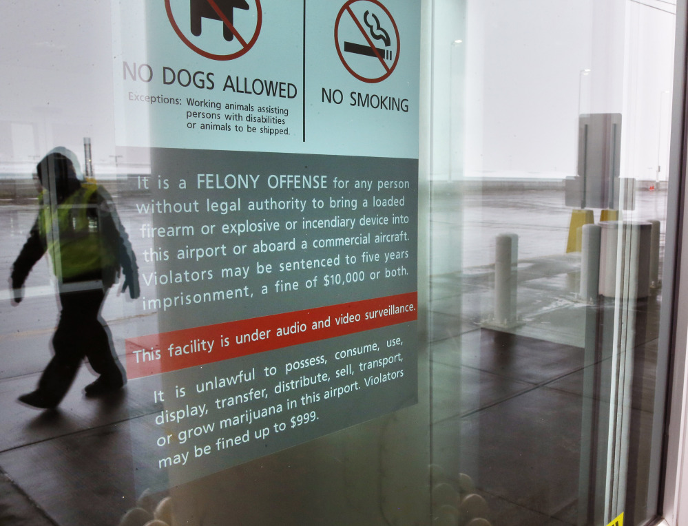 A security officer walks near a notice prohibiting marijuana possession at Denver International Airport.