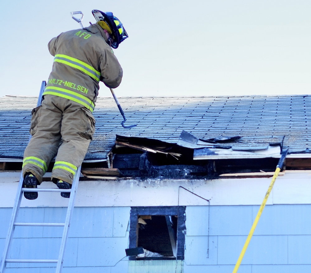 Thursday morning fire: Augusta firefighter Lars Schultz-Neilsen pulls down a section of burned garage roof on Brann Avenue in Augusta Thursday as he and other firefighters overhaul a fire-damaged garage to make sure there were no hot spots left.
