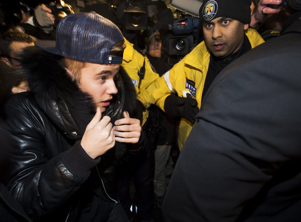 Canadian musician Justin Bieber is swarmed by media and police officers as he turns himself in to city police for an expected assault charge, in Toronto, on Wednesday.