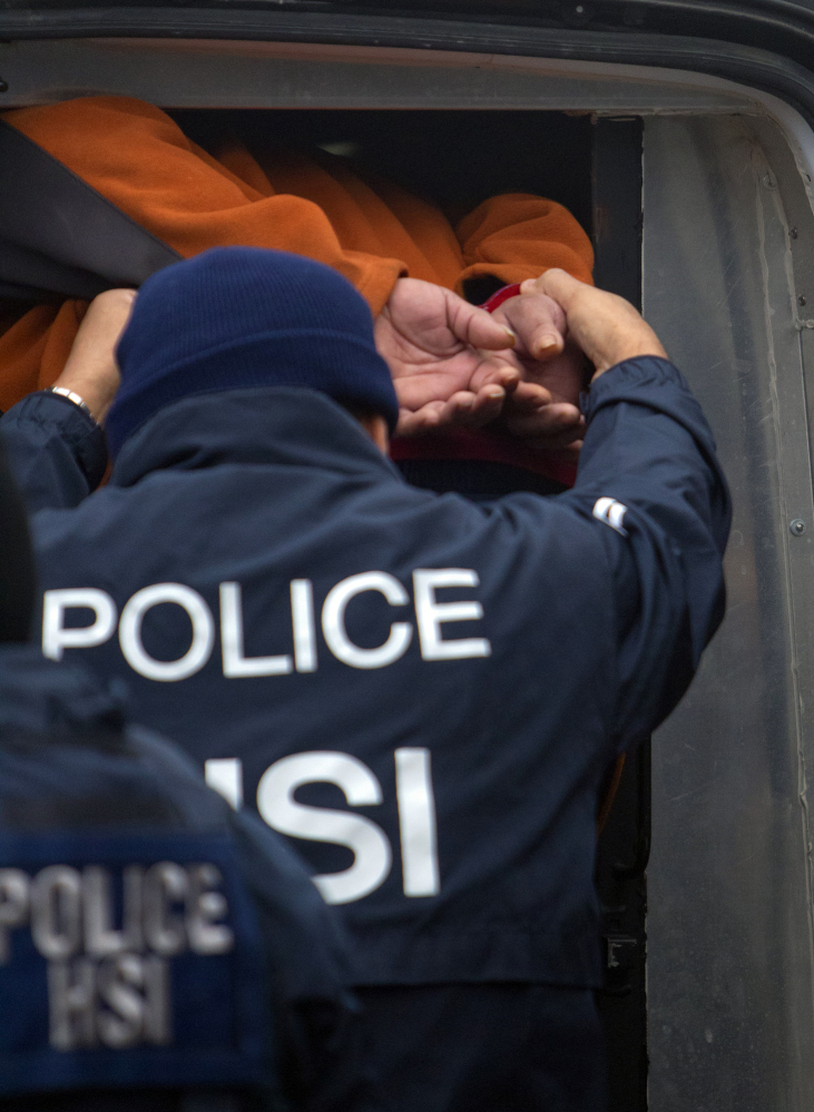 A federal agent helps a person into a vehicle after raiding a business, Thursday, Jan. 30, 2014, in southwest Houston. The raid was part of a crackdown on an alleged human smuggling ring operating in Texas and other states.