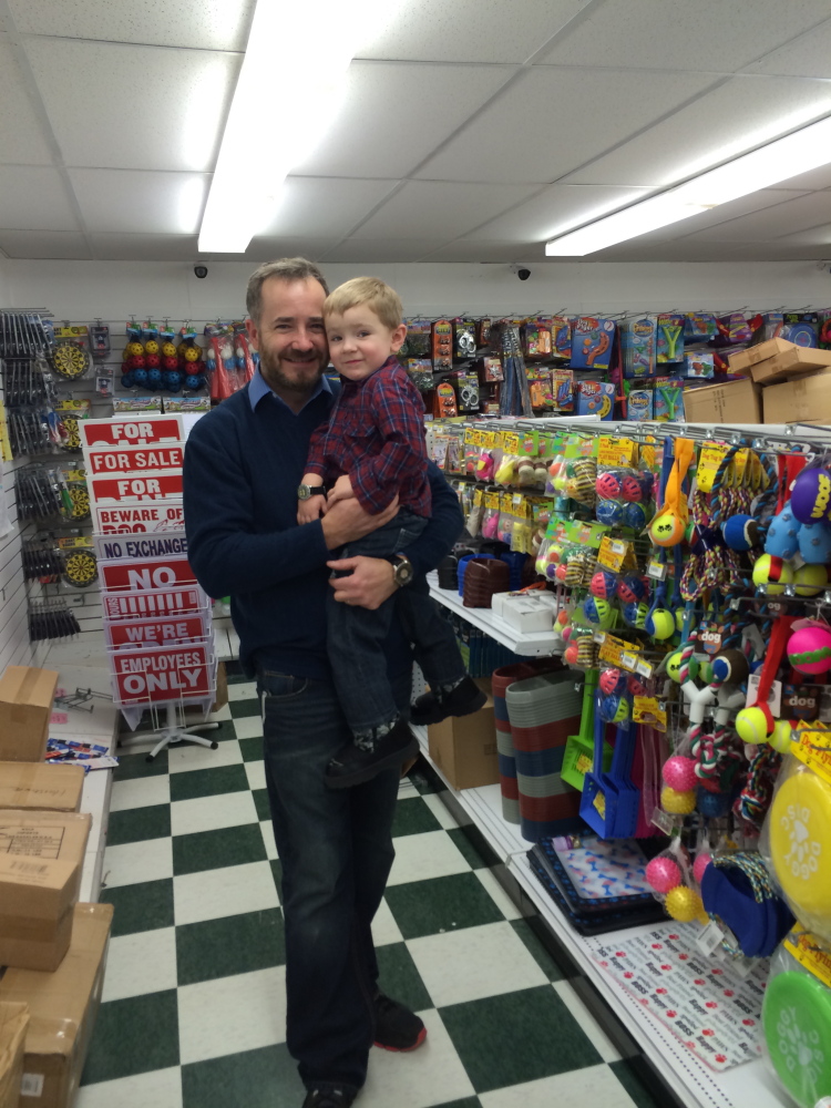 DOLLAR MAN: Thad Barber, owner of the new Dollar Deals variety store on Route 3 in South China, holds his 3-year-old son Tyler at Barber’s new store. The variety store is set to open on Feb. 8.