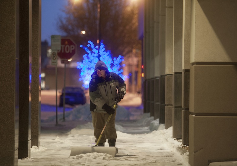 A worker clears the sidewalk at The Radisson Hotel in downtown Fargo, N.D., as temperatures of 20 degrees below zero and snow overnight brought out the shovels and snowblowers Monday, Jan. 27, 2014.The deep freeze that hit earlier this month has returned, bringing with it wind chills ranging from the negative teens to 40s, cancelations of schools, trains, flights and signs of resignation from parents forced to bring kids to work and residents who are tired of bundling up.