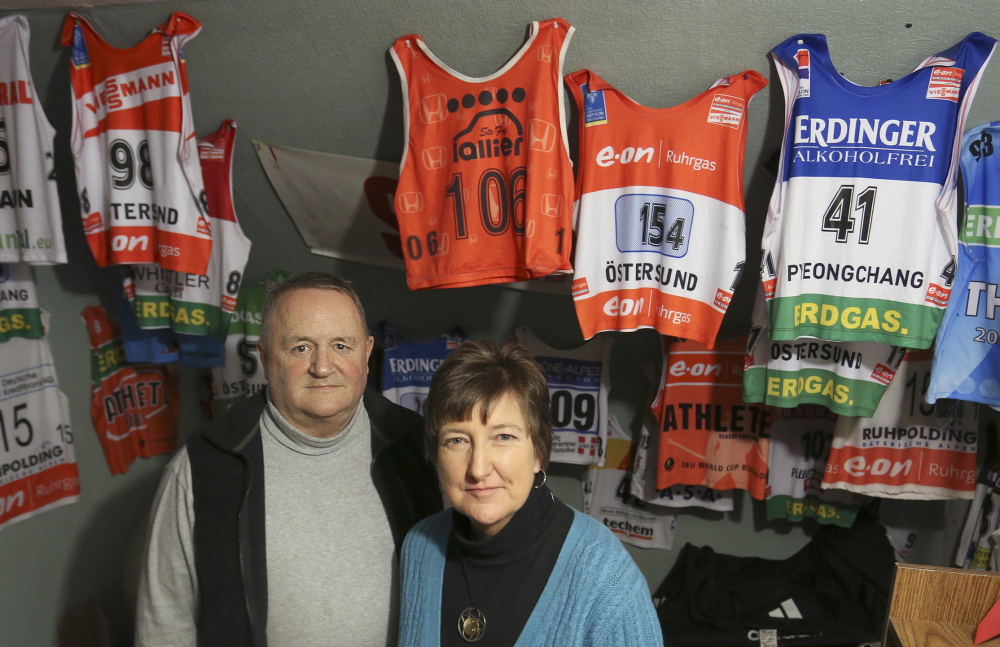 Chris and Debbie Currier pose in their home in front of bibs worn throughout the years by their son. In another room, Russell Currier’s medals hang from the arm of an exercise machine. The biathlete headed for the Olympics in Sochi, Russia, is markedly modest about his successes.