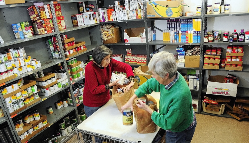 food pantry: Volunteers Elaine Brann, left, and Jeanne Rocque pack groceries for a client on Thursday at the Augusta Food Bank at St. Mark’s Episcopal Church in Augusta.
