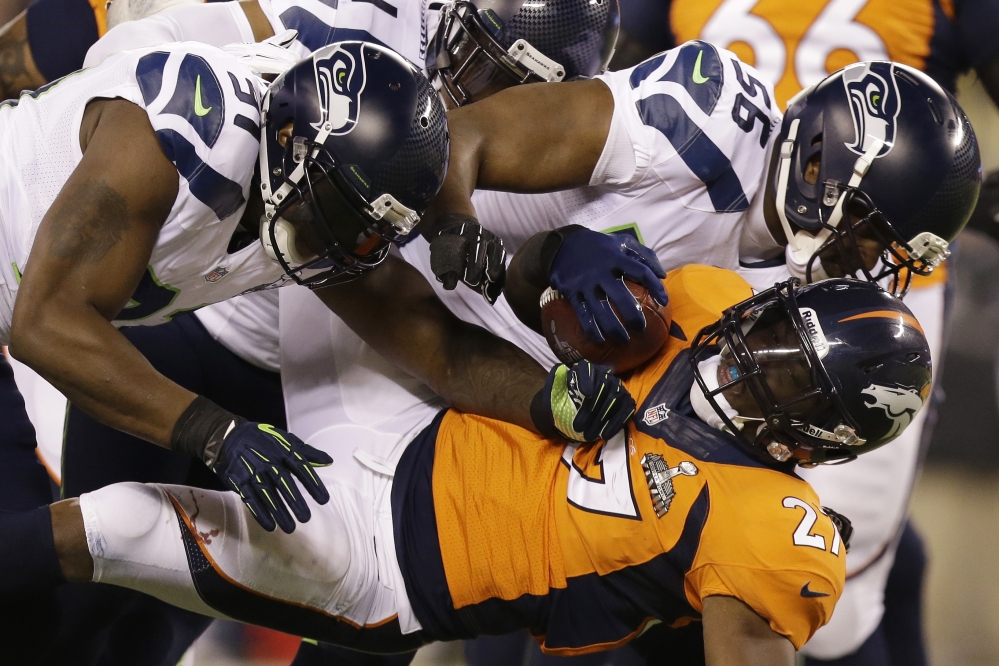 Denver Broncos’ Knowshon Moreno is tackled by Seattle Seahawks’ Chris Clemons, left, and Cliff Avril during the first half of the NFL Super Bowl XLVIII football game Sunday, Feb. 2, 2014, in East Rutherford, N.J.