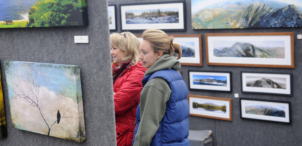 INSPECTORS: Dolly White, left, and her daughter, Becky, inspect panoramic photographs by Scott Perry on Sunday, Feb. 2, 2014, during the annual Cabin Fever Art Show at Longfellow’s Greenhouses in Manchester.