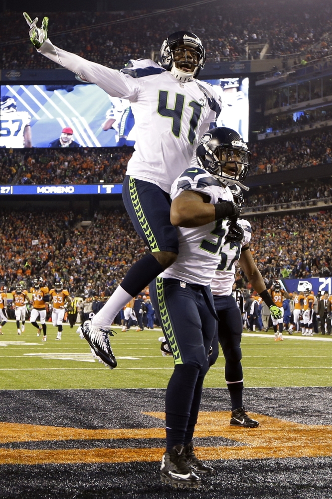 Seattle Seahawks' Byron Maxwell, top, celebrates with teammate Malcolm Smith after Smith scored a touchdown during the first half of the NFL Super Bowl XLVIII football game Sunday, Feb. 2, 2014, in East Rutherford, N.J. (AP Photo/Mark Humphrey)