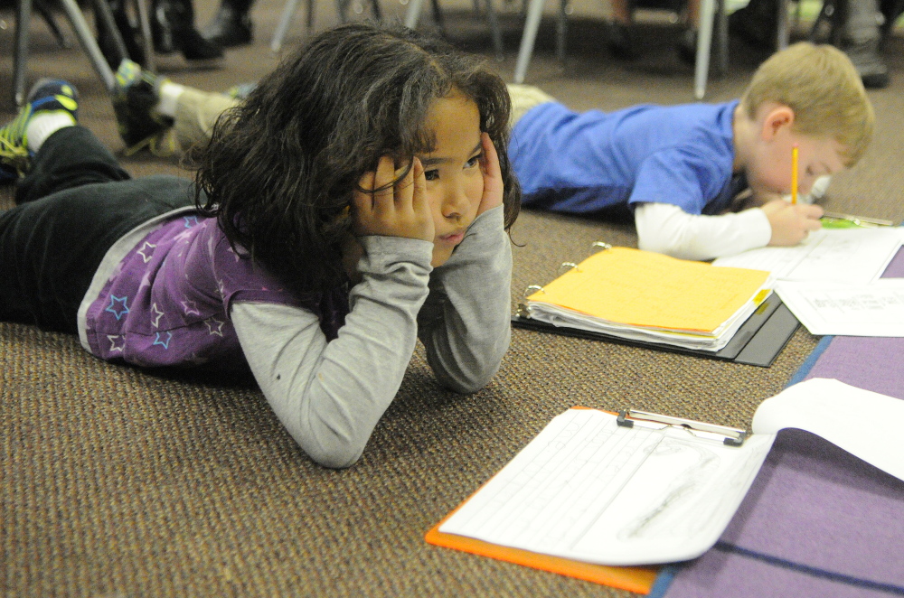 Zion Armstrong, left, thinks about what to write next as classmate Justin Stein works next to her on the floor during a writing workshop last fall in Jessica Gurney’s classroom at Manchester Elementary School.