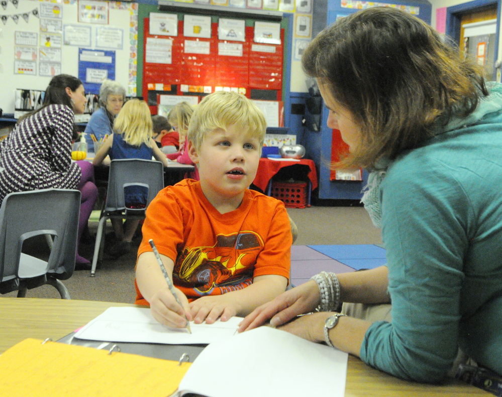 Mason Pare, left, tells Ed Tech Jessica Dwyer about his plans to write about monster trucks during a writing workshop last fall in Jessica Gurney’s classroom at Manchester Elementary School.