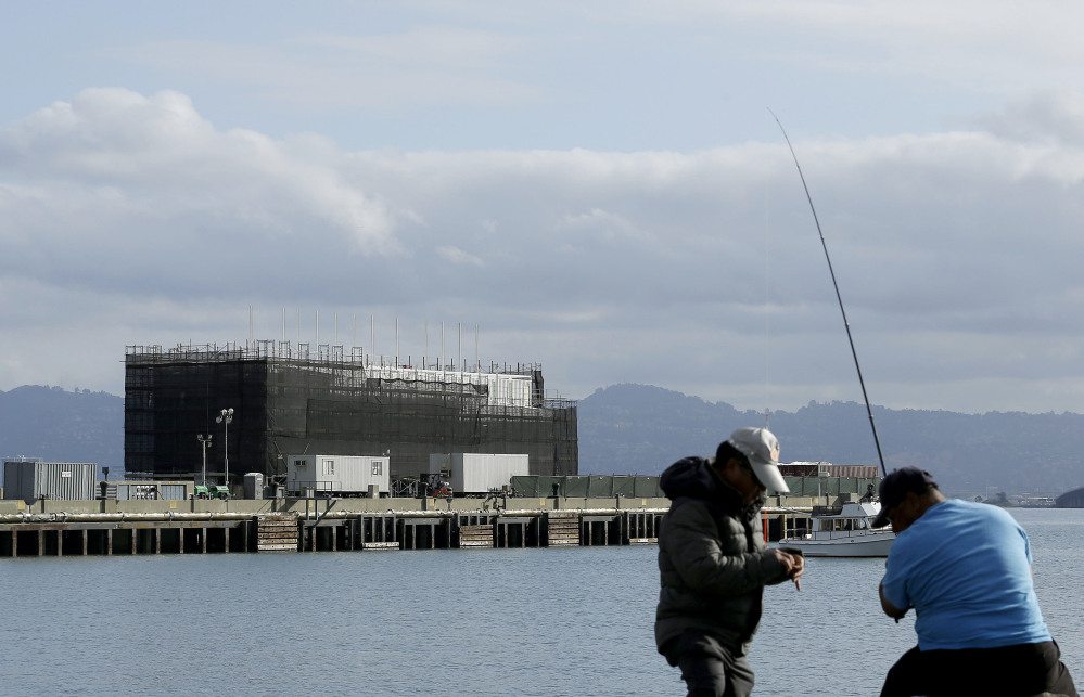 In this Tuesday, Oct. 29, 2013, file photo, two men fish in the water in front of a Google barge on Treasure Island in San Francisco. A state agency says Google must move its mystery barge from a construction site on an island in the middle of the San Francisco Bay because the permits are not in order.