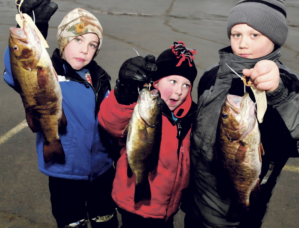 STIFF COMPETITION: From left holding their bass entries are Nikus Stetson, Maddux Duplessis and Zack Knight, all of whom took part in the 23rd annual Children’s Ice Fishing Frenzy sponsored by the Oakland Recreation Department and Oakland Lions Club on Sunday, Feb. 2, 2014. First, second and third place prizes were awarded in 10 categories from fish caught in Belgrade Lakes waters.