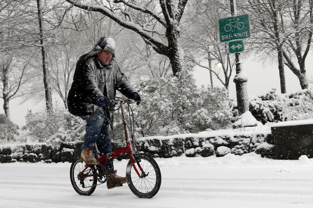 A cyclist makes his way up the Hudson River Greenway as heavy snow falls Monday in New York.