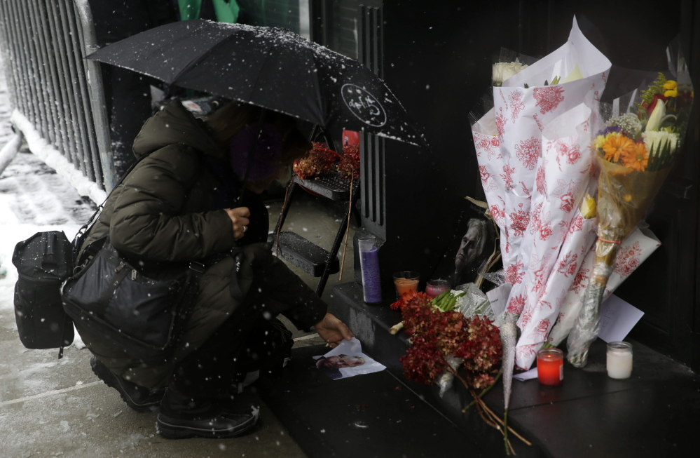 A woman unfolds a picture of Philip Seymour Hoffman on Monday at a makeshift memorial in front of the building where his body was found. Hoffman, 46, was found dead Sunday in his New York apartment of a suspected drug overdose.