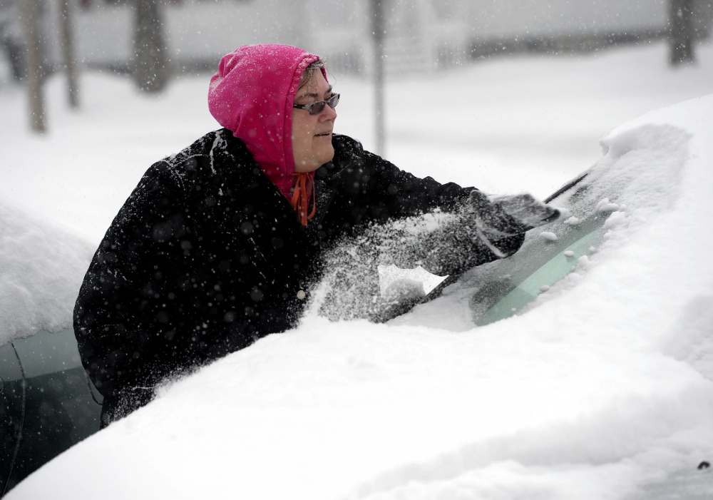 Lori Raftis of Saco clears snow off her car during Wednesday’s snowstorm.