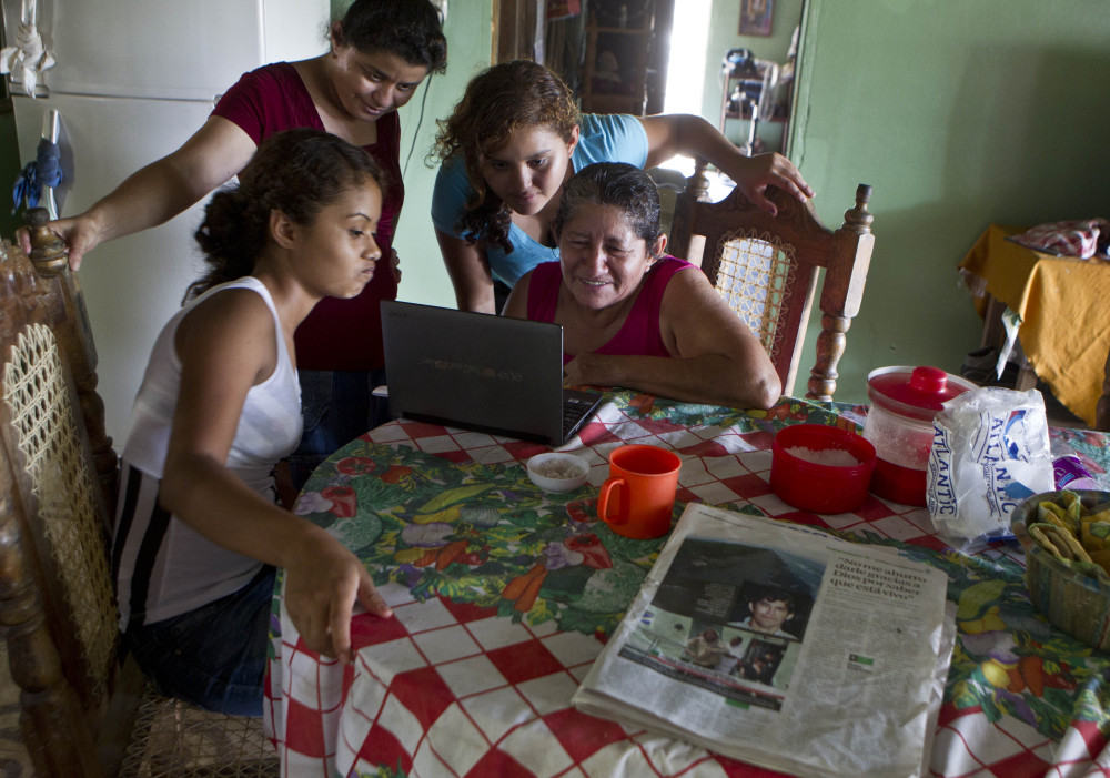 The mother of sea survivor Jose Salvador Alvarenga, Maria Alvarenga, right, his daughter Fatima Alvarenga, second right, and other family members gather at the kitchen table to video chat with relatives living in Maryland, in Garita Palmera, El Salvador on Tuesday. The account of Alvarenga’s survival after more than 13 months in an open boat has proven a double miracle for his family, who lost touch with him years ago and thought he was dead.