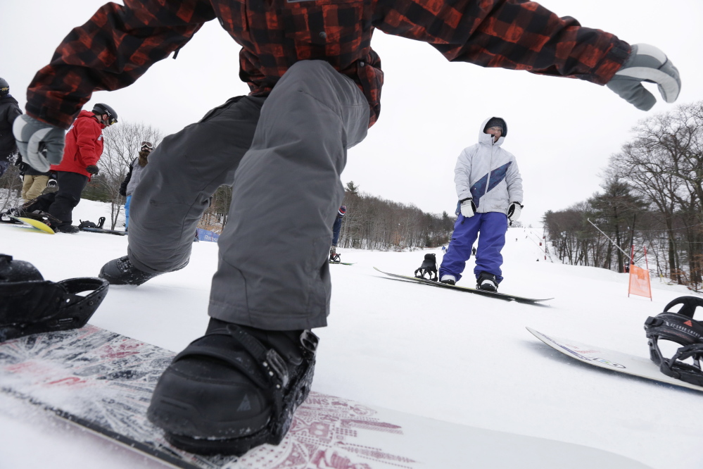 Snowboarders traverse a slope as they make their way toward a chairlift at Blue Hills Ski Area in Canton, Mass., last December. Massachusetts ski areas are among those threatened by warming winters.