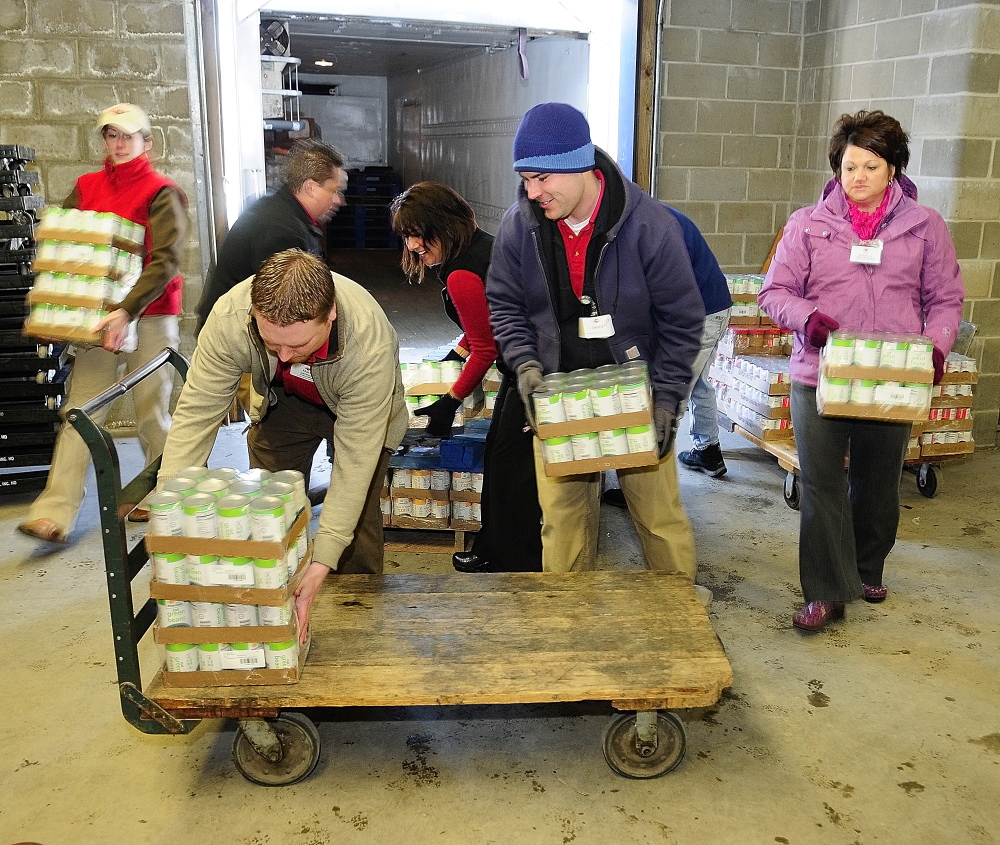 Staff photo by Joe Phelan HELPING HANDS: Hannaford employees from the company’s two Augusta stores load donated food onto a cart on Friday February 7, 2014 at the Augusta Food Bank’s warehouse.