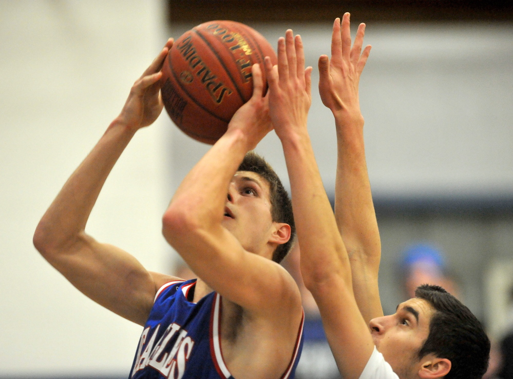 Staff photo by Michael G. Seamans Messalonskee High School's Jordan Holmes, 23, takes a shot as Lawrence High School's Seth Powers, 15, defends, at Lawrence High School in Fairfield on Friday.