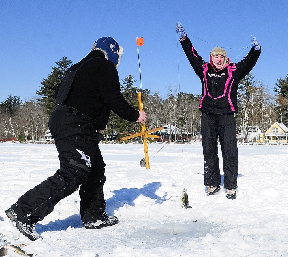 Victory: Collin Acord, left, holds up a trap, while Kyla Johansen, celebrates after pulling up a bass Saturday during an RSU 2 fundraising ice fishing tournament at the Cochnewagen Lake Town Landing in Monmouth.
