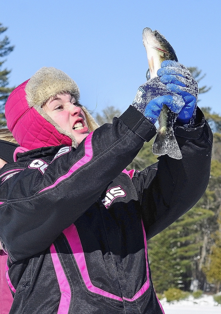 Goal achieved: Kyla Johansen celebrates after pulling up a bass Saturday on during an RSU 2 fundraiser ice fishing tournament at the Cochnewagen Lake Town Landing in Monmouth.