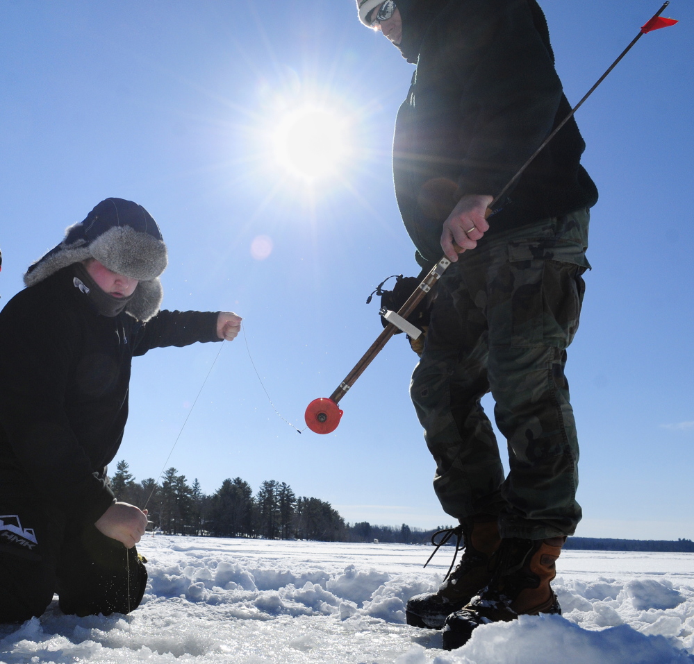 A FINE LINE: Collin Acord, left, pulls up a fish as Ron Emmons holds on to a trap Saturday during an RSU 2 fundraising ice fishing tournament at Cochnewagen Lake Town Landing in Monmouth.