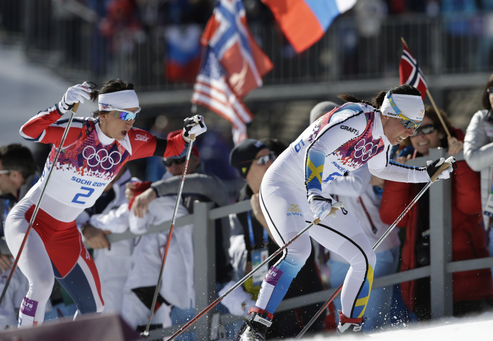 Norway’s gold medal winner Marit Bjoergen, left, and Sweden’s silver medal winner Charlotte Kalla climb a hill during the women’s cross-country 15k skiathlon Saturday.
