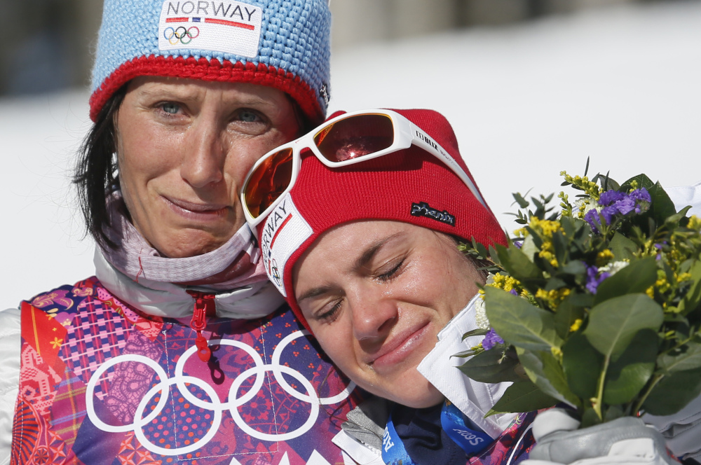 Norway’s gold medal winner Marit Bjoergen, left, hugs bronze medal winner Heidi Weng during the flower ceremony of the women’s cross-country 15k skiathlon at the 2014 Winter Olympics.