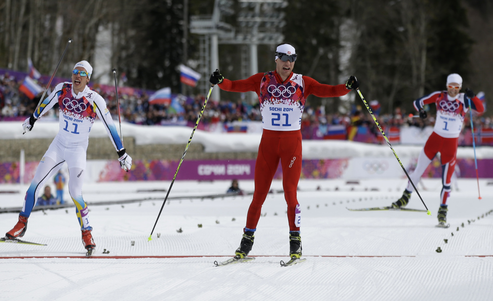 Switzerland’s Dario Cologna, center, crosses the finish line to win the men’s cross-country 30k skiathlon ahead of Sweden’s Marcus Hellner, left, and Norway’s Martin Johnsrud Sundby, right, at the 2014 Winter Olympics on Sunday.