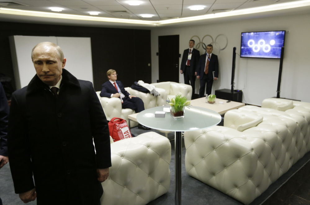 Russian President Vladimir Putin waits in the presidential lounge to be introduced at the opening ceremony of the 2014 Winter Olympics on Friday in Sochi, Russia. Behind him, a TV screen shows four of the Olympic rings opening at the start of the ceremony, while the fifth ring remains closed.