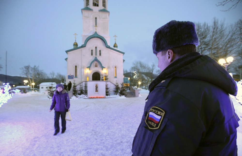A policeman watches a believer leaving the Cathedral of the Resurrection of Christ in Yuzhno-Sakhalinsk on Sunday, Feb. 9. Law enforcement officers detained a man, who worked as a security guard, and were trying to determine why he attacked the Russian Orthodox cathedral in the city of Yuzhno-Sakhalinsk.