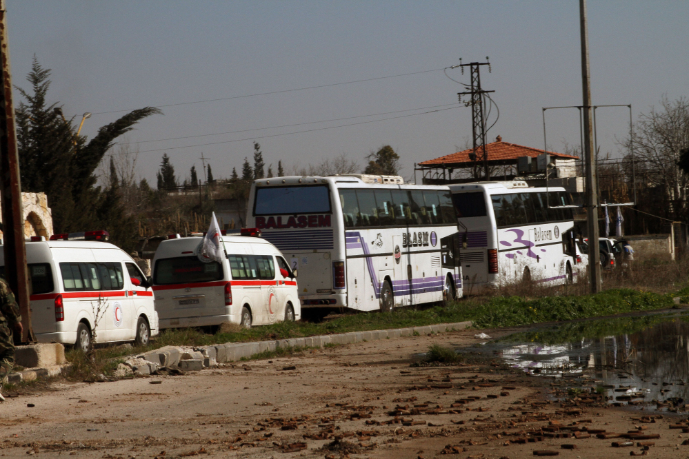 Some Syrian people on two buses followed by the Syrian Arab Red Crescent’s vehicles evacuate Syria’s battleground city of Homs, Friday.
