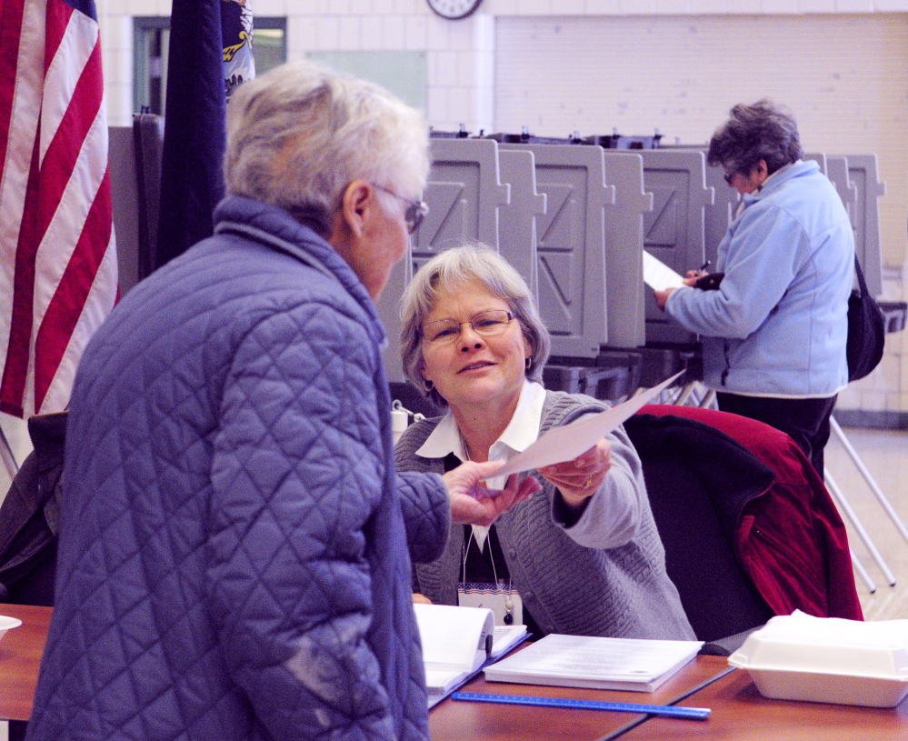 BUDGET FINALIZED: Election worker Jan Tewksbury, center, hands a ballot to a voter Tuesday during a vote on the school budget at the Winthrop Town Office.