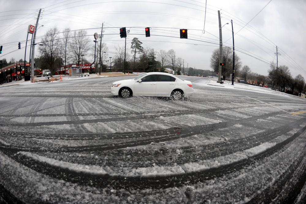 In this photo taken with a fisheye lens, a lone motorist drives through a slick intersection during the morning commute on Wednesday in Atlanta.