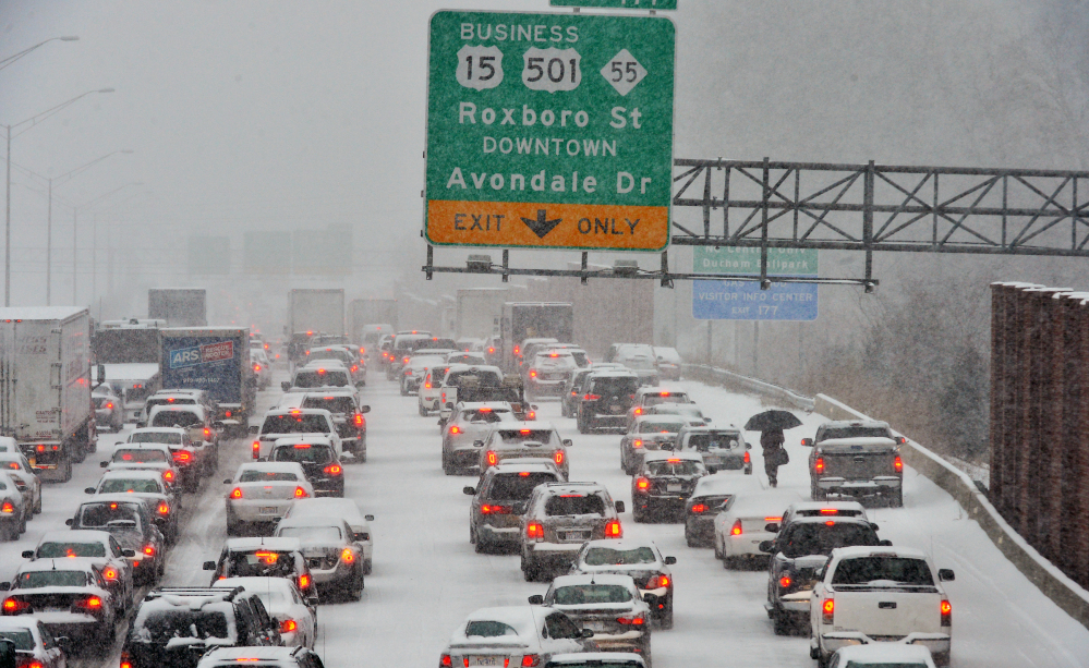 A motorist, right, who abandoned a vehicle, walks through stopped traffic on northbound Interstate 85 during a storm Wednesday in Durham, N.C.